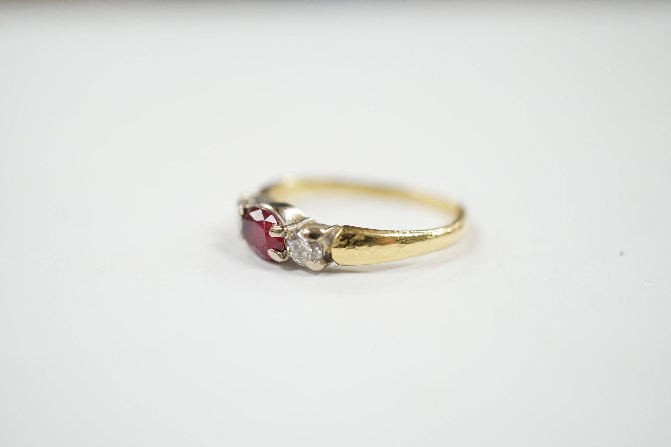 A modern 18ct gold, ruby and diamond set three stone ring, shank misshapen, gross weight 2.9 grams.